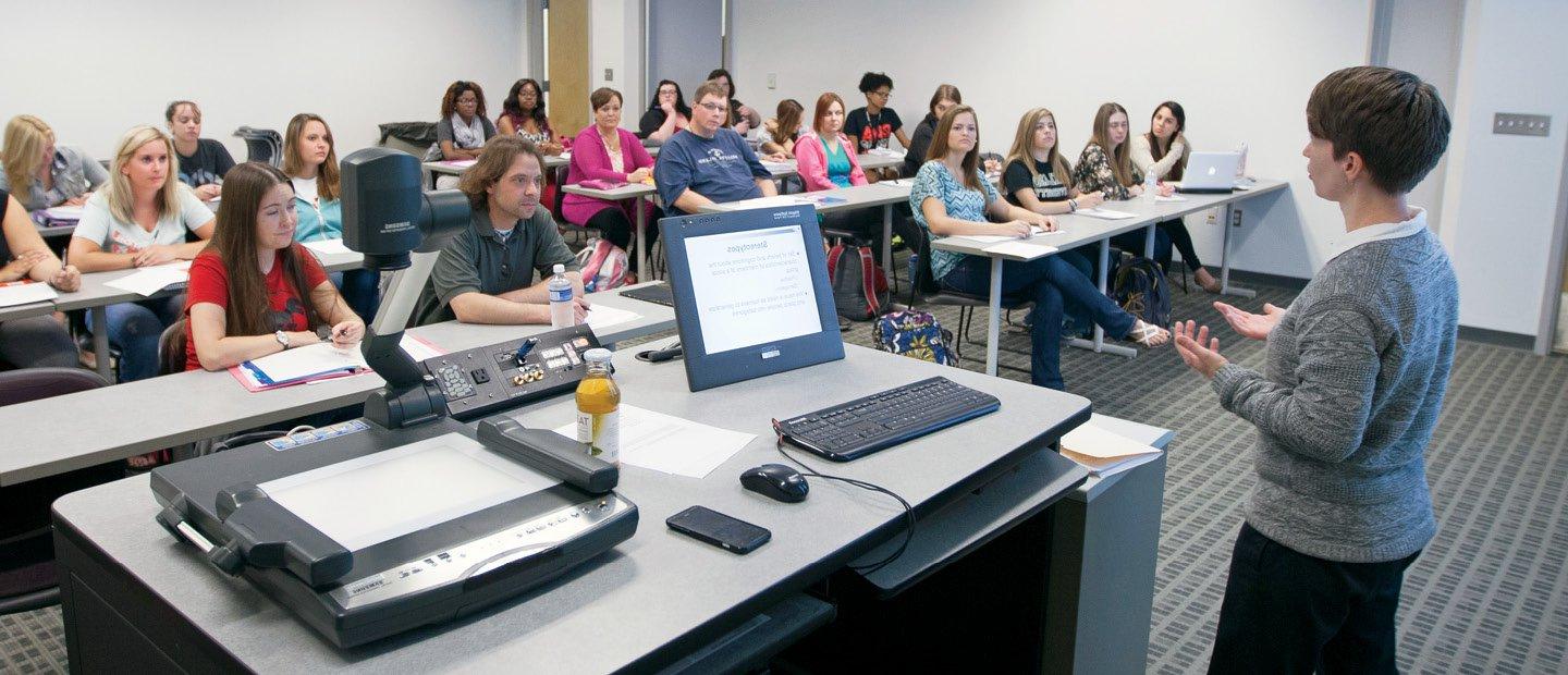A professor teaching in front of a room full of students.